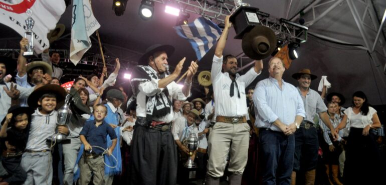 Festejos de la aparceria A poncho y espuelas, su presidente levanta la copa ante la mirada del intendente de tacuarembó, Wilson Esquerra.