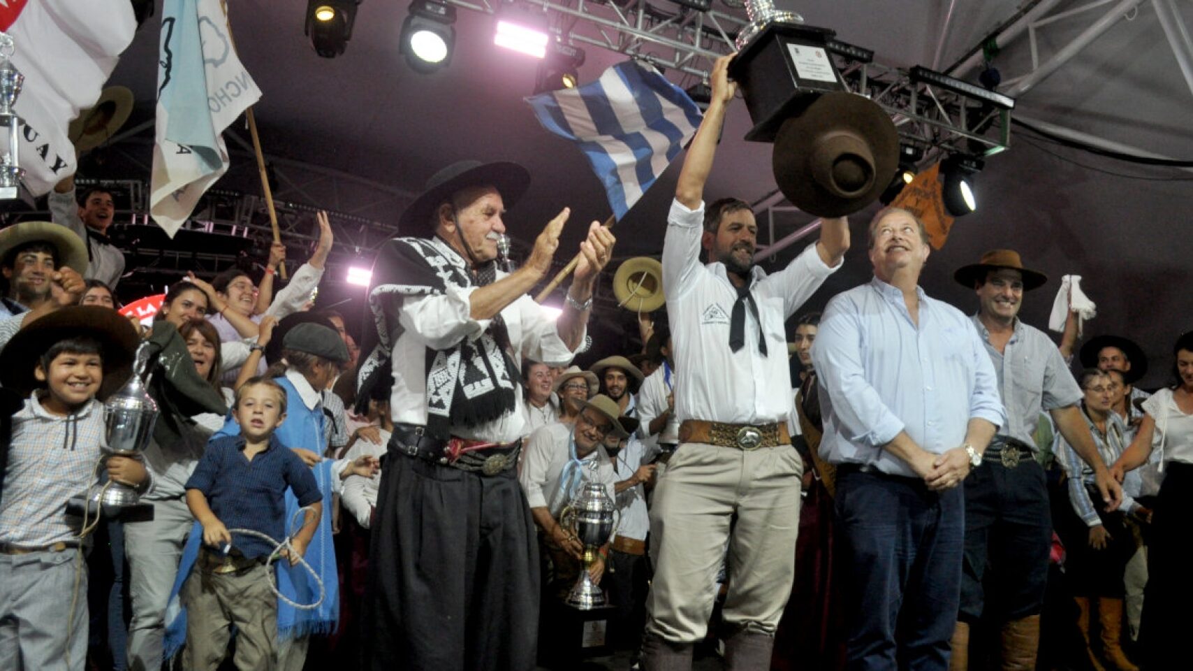Festejos de la aparceria A poncho y espuelas, su presidente levanta la copa ante la mirada del intendente de tacuarembó, Wilson Esquerra.