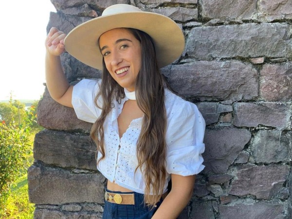 Catherine Vergnes con un sombrero frente una piedra de tamaño importante.